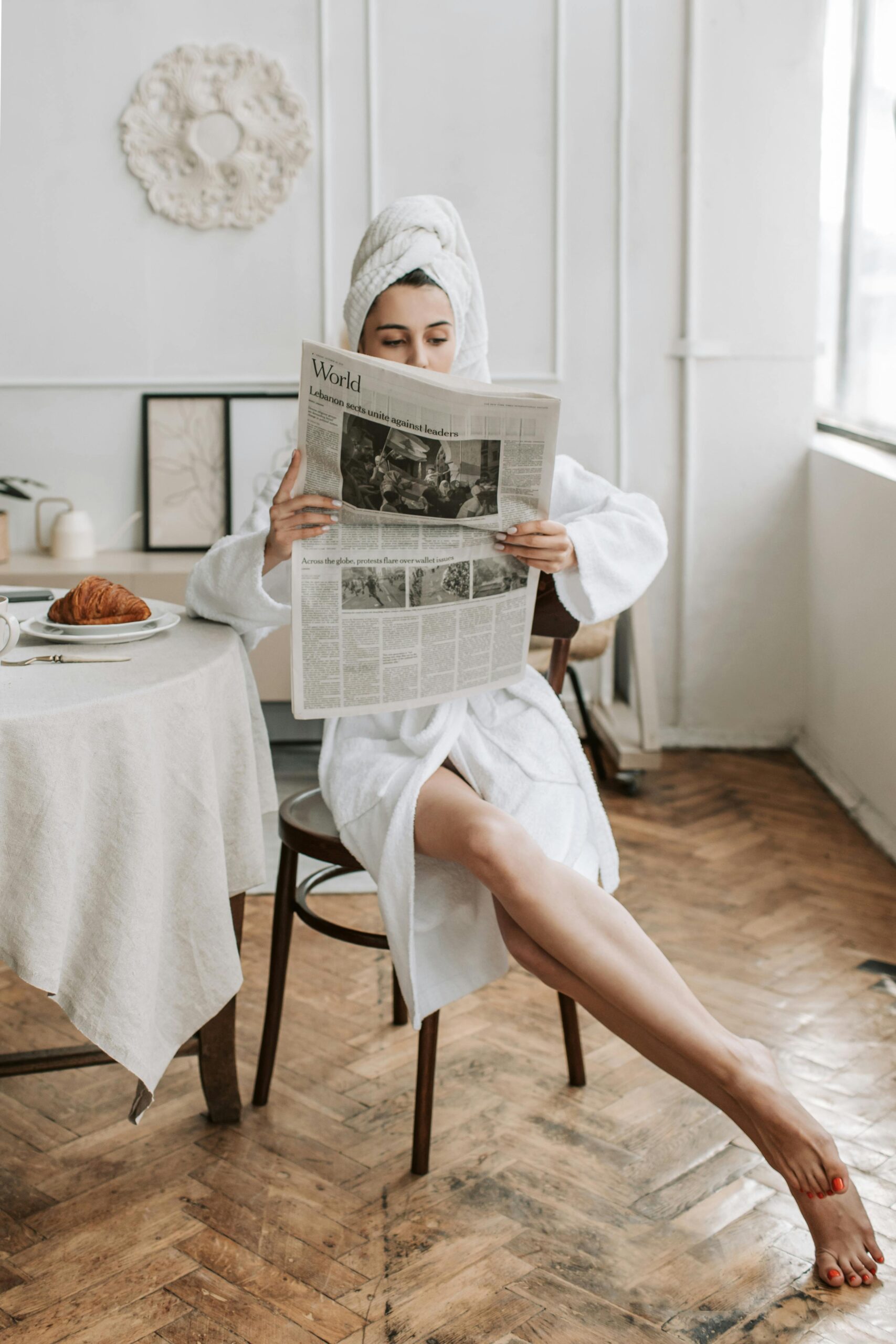 Woman in a robe reading the newspaper.